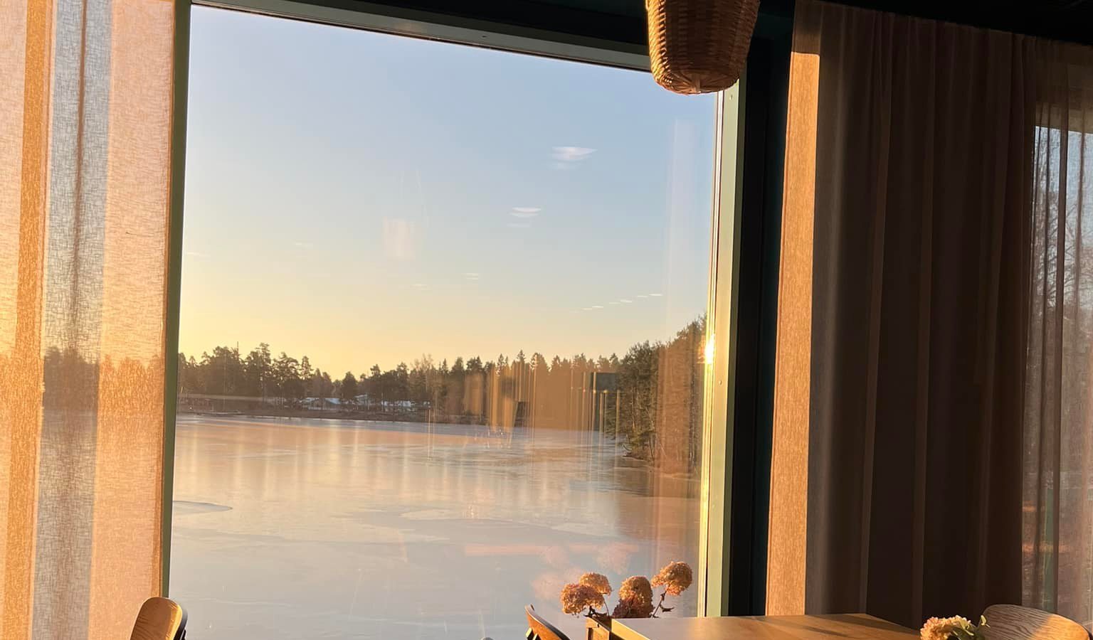 Cafe Hillan sali iltavalossa, suuri ikkuna aukeaa Huutjärvelle